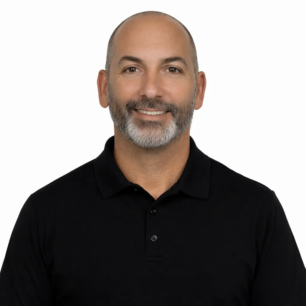 Chris Corbett headshot - Man wearing a black polo shirt on a white background